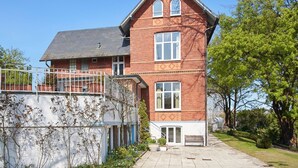 A two-story brick house with a balcony, a small garden, and a paved driveway. - Double room "Seestern" - Quiet time-out with sea view on the second floor - (Timmendorfer Strand)