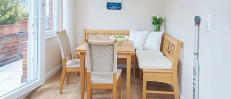 A dining area with a wooden table and chairs, a bench, a vase with flowers, and a sign on the wall.