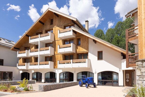 A multi-story building with a wooden facade, balconies, and a reception area. - Apartment in Serre-Chevalier near Ski Slopes (Saint Chaffrey)