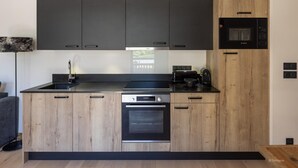 A modern kitchen with dark cabinets, a built-in oven, and a microwave. - Apartment in Chantemerle with Family Ski Fun (Saint Chaffrey)