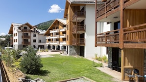 Un hotel moderno de varios pisos con balcones de madera y un césped bien cuidado.