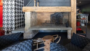 Ein rustikaler Innenraum mit Kamin aus Stein, Holzbalken und Wand mit Hundeohrenmuster.