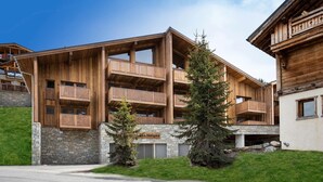 A multi-story wooden building with balconies, stone foundation, and a sign reading "Hotel Neiges."