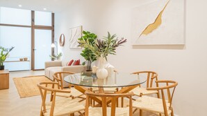 A modern dining area with a glass table and wooden chairs, surrounded by white walls and minimalist decor. - Flats - Poeta Serrano (Valencia)
