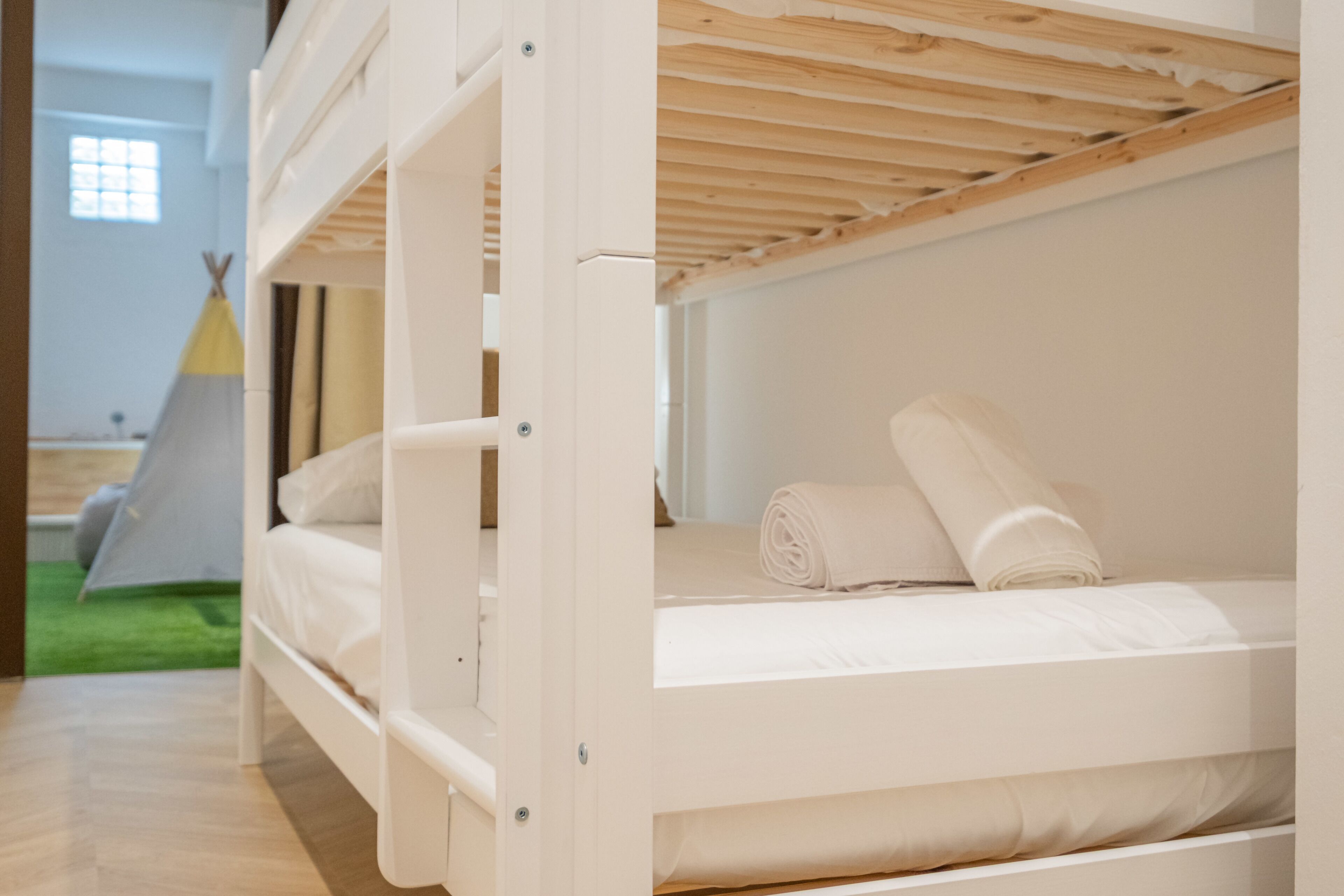 A bunk bed with white bedding and a wooden ceiling.