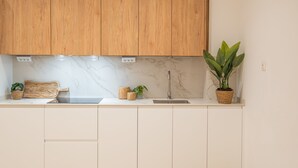 A kitchen with wooden cabinets, a marble countertop, a sink, and potted plants. - Flats - Poeta Serrano (Valencia)