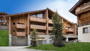 Un edificio de madera de varios pisos con balcones, base de piedra y un letrero que dice 'Hotel Neiges'.