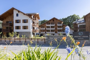 Uma hospedaria moderna com fachada de madeira e várias varandas, chamada 'Cristal Lodge'.