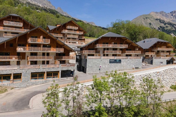 A mountain lodge with multiple wooden buildings, balconies, and a stone facade.