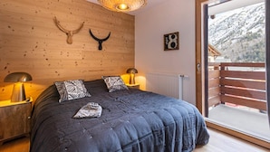 A bedroom with a large bed, wooden walls, and a view of a snowy mountain.