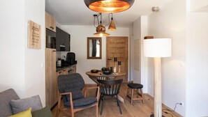 Un espacio habitable compacto con comedor, kitchenette y una lámpara de pie grande.