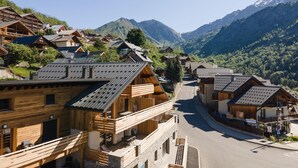 Un pueblo de montaña con edificios de madera, una calle y vistas a montañas nevadas.