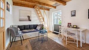 A cozy living room with a wooden ceiling, a sofa, a coffee table, and a ladder. - Guesthouse 'Charming Lütt Hus' with Private Terrace, Shared Garden and Wi-Fi (Damlos)
