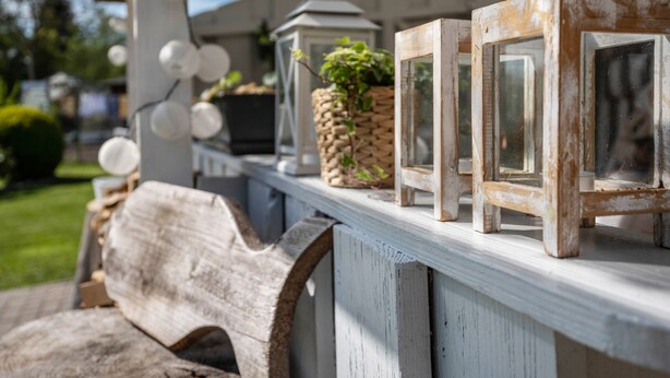 A rustic outdoor setting with a wooden bench, a lantern, and a small wooden table with decorative items. - Guesthouse 'Charming Lütt Hus' with Private Terrace, Shared Garden and Wi-Fi (Damlos)