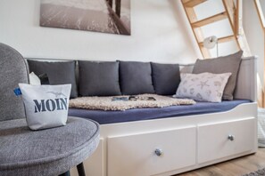 Ein modernes Wohnzimmer mit einer Couch, einem Sessel und einem Bett mit Kopfteil.