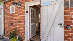 A brick building with a white door and a blue sign reading 'Nordlich'. - Guesthouse 'Charming Lütt Hus' with Private Terrace, Shared Garden and Wi-Fi (Damlos)