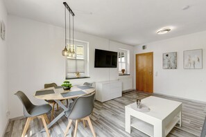 Un espace repas moderne avec une table en bois, des chaises grises et une table basse blanche.