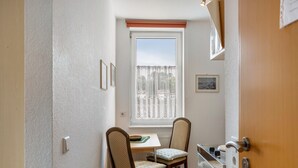 A small room with a window, a table, two chairs, a radiator, and a door.
