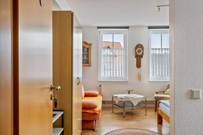 A room with a bed, a table, a chair, a radiator, and a window with a view of a building. - Apartment with Wi-Fi (Naumburg)