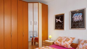 Ein Schlafzimmer mit einem Bett, einem Kleiderschrank, einem Nachttisch und zwei gerahmten Bildern an der Wand.