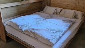 Een houten slaapkamer met een bed, planken en een raam.
