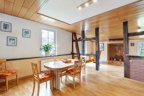 Ein Essbereich mit Holztisch und -stühlen, einem Fenster mit Pflanze und einem Kamin aus Ziegelsteinen.