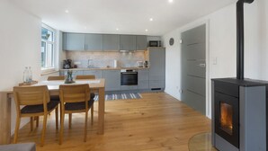 Une cuisine moderne avec des meubles gris, une table à manger en bois et un poêle à bois.