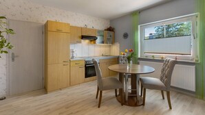 Una cocina moderna con armarios de madera, una mesa de comedor con sillas y un ventanal con persianas.