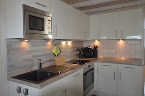 Una cocina moderna con microondas integrado, lavaplatos de acero inoxidable y tostadora.