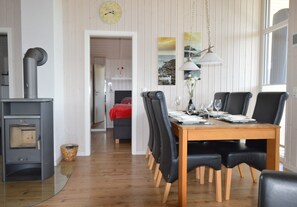 A dining area with a wooden table, black chairs, a red sofa, a fireplace, and a clock on the wall.