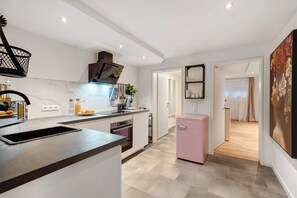 A modern kitchen with a sink, stove, and a pink refrigerator.