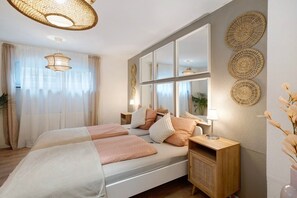 A bedroom with a large bed, bedside tables, a mirror, and decorative wall art.