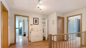 A hallway with wooden flooring, a white wardrobe, a framed picture on the wall, and a door leading to another room. - Apartment 'Sigrid' with Shared Garden, Balcony and Wi-Fi (Forchheim)