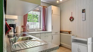 A kitchen with a sink, countertop, cabinets, a window with curtains, a radiator, and a wall calendar. - Apartment '1, 45qm' with Mountain View, Shared Terrace and Wi-Fi (Oberwolfach)