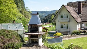 A house with a stone fireplace, a balcony, and a garden. - Apartment '2, 45qm' with Mountain View, Shared Terrace and Wi-Fi (Oberwolfach)