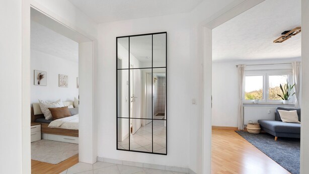 Un salon moderne avec un grand miroir, un canapé et une vue sur l’extérieur.