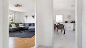 Un intérieur moderne avec un canapé gris, un plancher en bois et un coin cuisine.