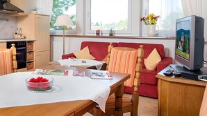 Una sala de estar acogedora con un sofá rojo, una mesa de madera y un televisor.