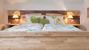 Una cama doble con cubrecama floral, dos mesitas de noche con lámparas y un cabecero de madera.