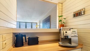 A compact kitchen with a coffee machine, a kettle, and a toaster on the counter.