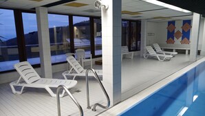 A swimming pool area with lounge chairs and a view of the outdoors.