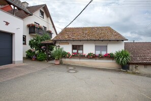 Un bâtiment à deux étages, avec un toit recouvert de tuiles, une enseigne indiquant « Ferienhaus » et des jardinières sur le balcon.