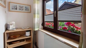 A kitchen with a coffee maker, a window with blinds, and a view of flowers outside. - Holiday Home 'Am Blumengässle' with Balcony and Wi-Fi (Müllheim im Markgräflerland)