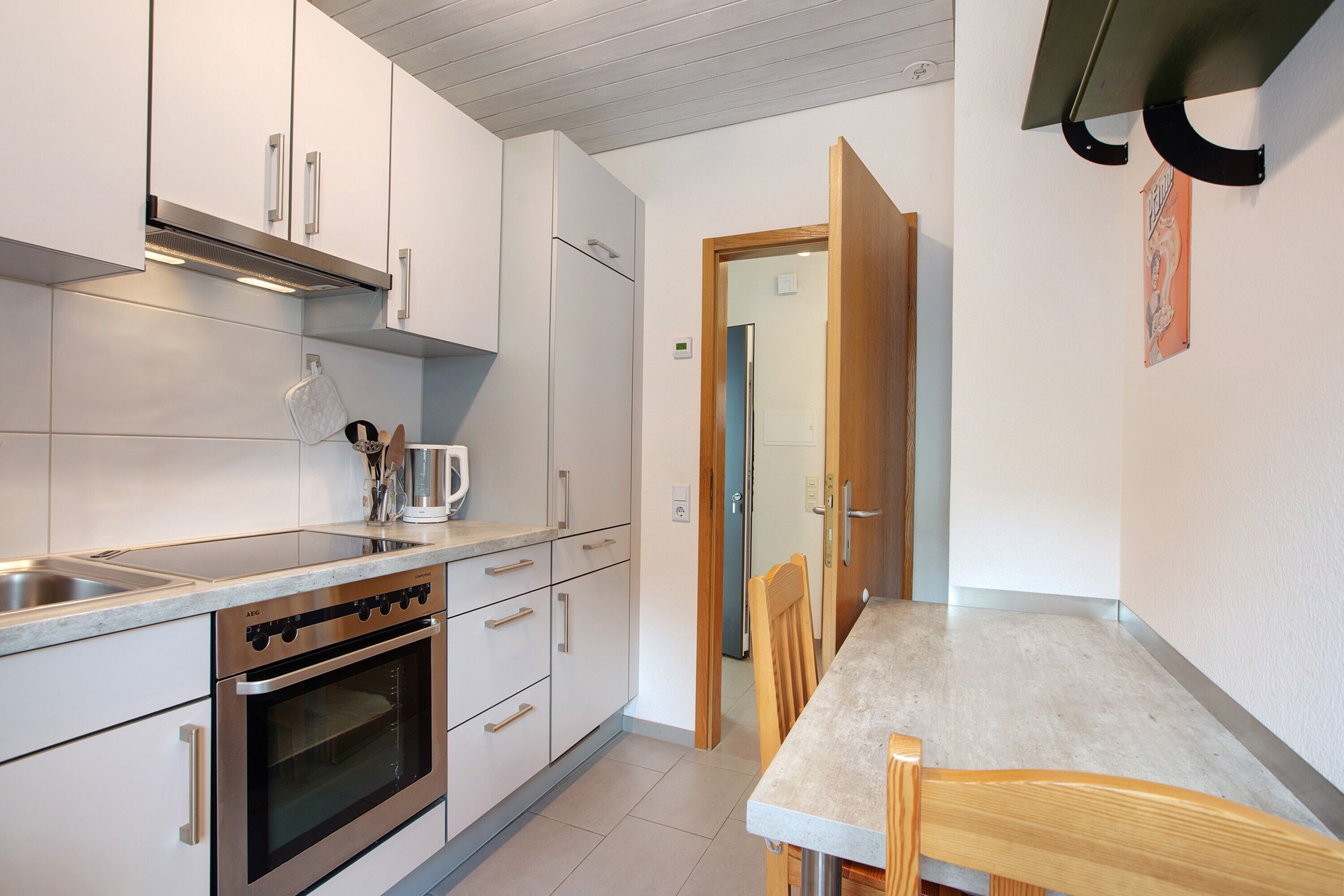 A modern kitchen with stainless steel appliances, white cabinetry, and a wooden dining table.
