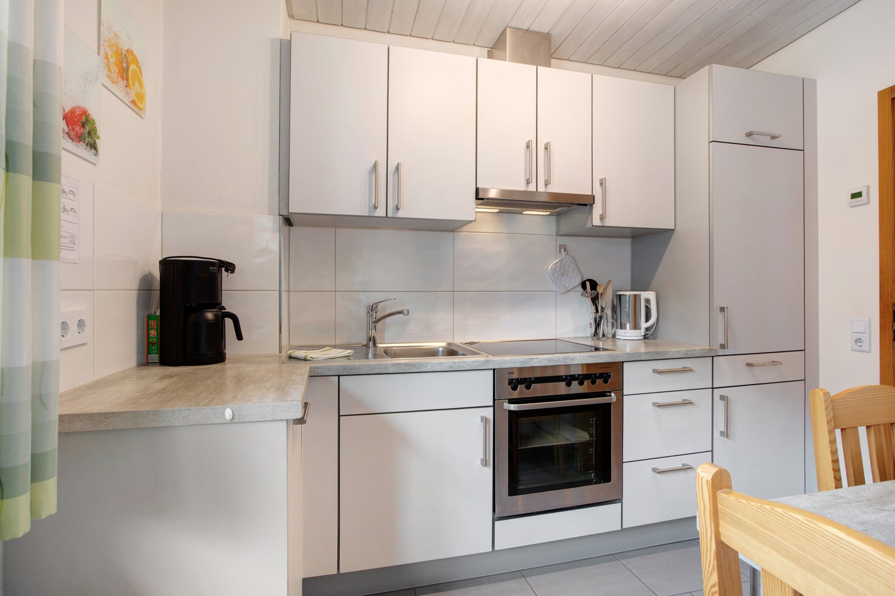A modern kitchen with white cabinets, stainless steel appliances, a coffee maker, and a kettle.