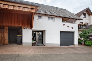 Ein Gebäude mit hölzernem Eingang, einer Garage und einem Balkon mit Blumen.