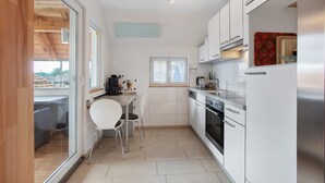 Una cocina funcional con armarios blancos, una mesa de comedor con sillas y una ventana.