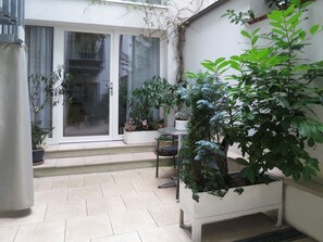 Un espace extérieur aménagé avec des plantes en pot, une table et une chaise.