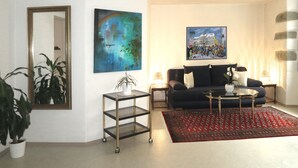 A living room with a sofa, a coffee table, a rug, a plant, and two paintings.
