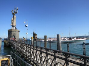 Une jetée ornée d’une statue, une petite tour et un bateau amarré.